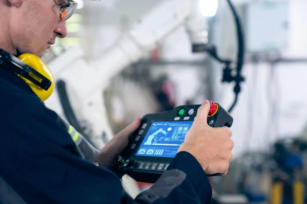 young factory worker working with adept robotic arm